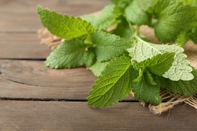 Photo of Fresh lemon balm leaves on wooden table, closeup. Space for text