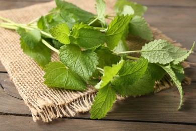 Photo of Fresh lemon balm leaves on wooden table, closeup