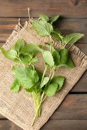 Photo of Fresh lemon balm leaves on wooden table, top view