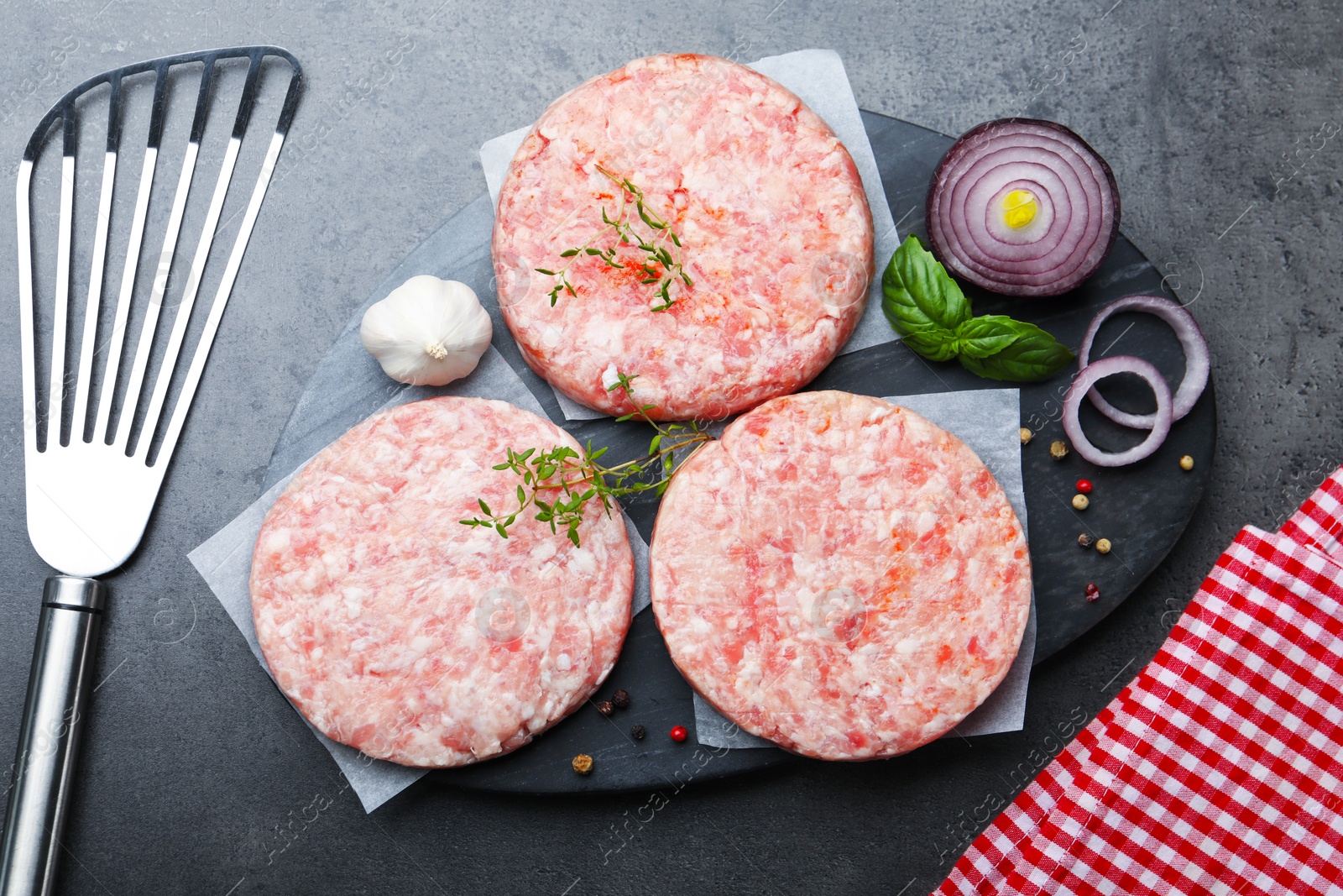 Fresh raw patties for burger and spices on grey table, flat lay Photo of Fresh raw patties for burger and spices on grey table, flat lay