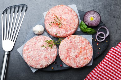 Photo of Fresh raw patties for burger and spices on grey table, flat lay
