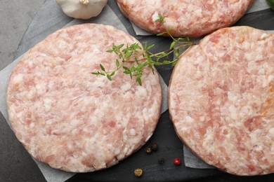Photo of Fresh raw patties for burger and spices on grey table, top view