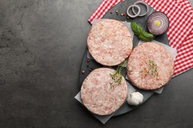 Photo of Fresh raw patties for burger and spices on grey table, top view. Space for text