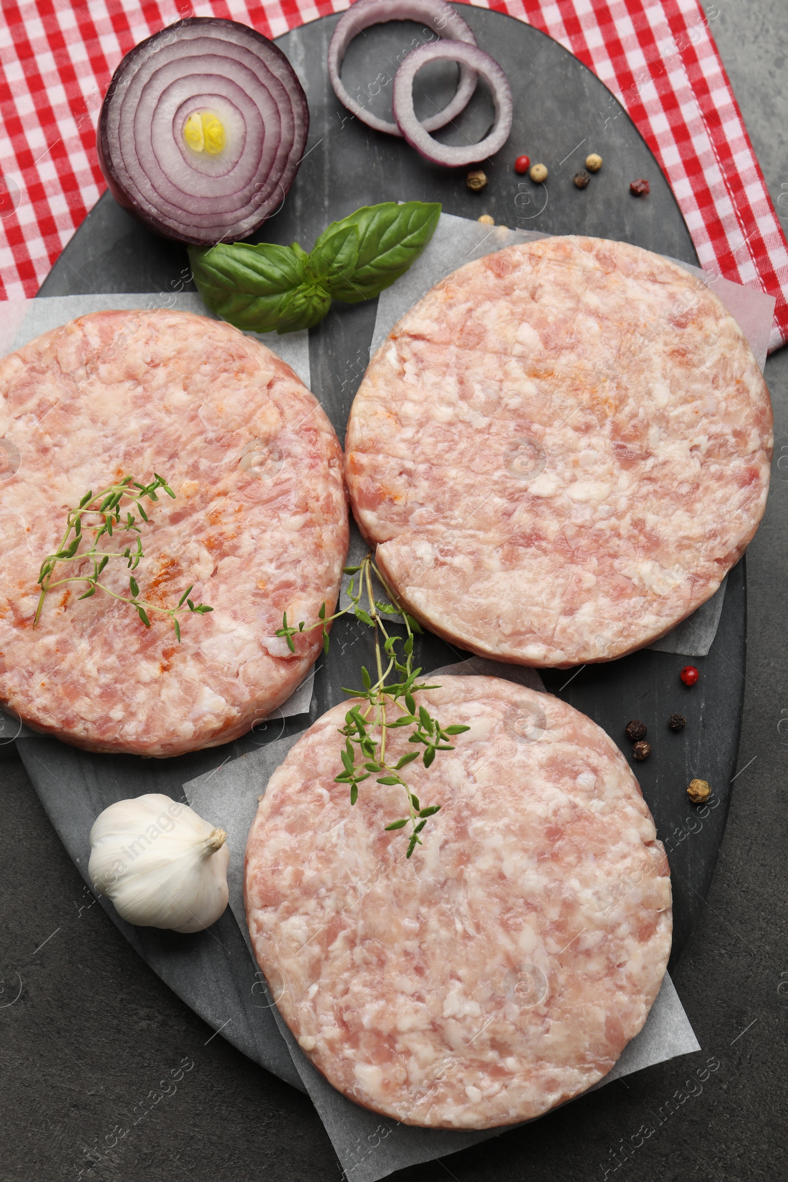 Fresh raw patties for burger and spices on grey table, top view Photo of Fresh raw patties for burger and spices on grey table, top view