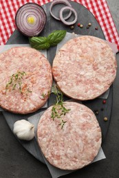 Photo of Fresh raw patties for burger and spices on grey table, top view