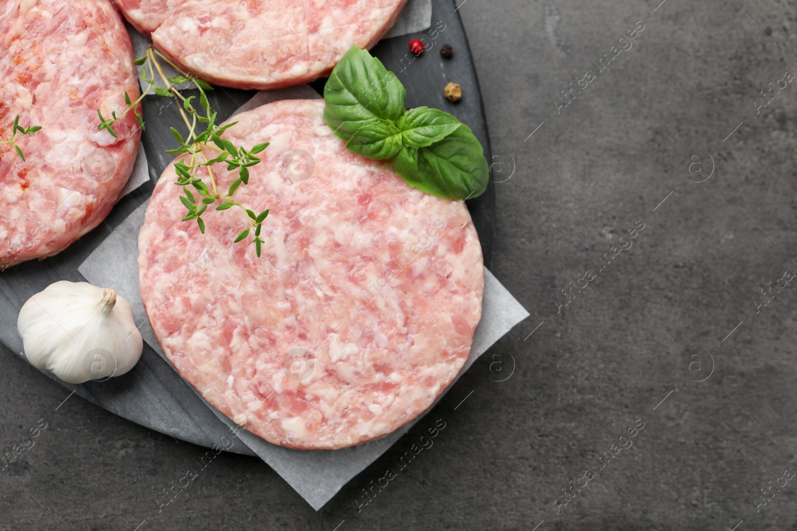 Fresh raw patties for burger and spices on grey table, top view. Space for text Photo of Fresh raw patties for burger and spices on grey table, top view. Space for text