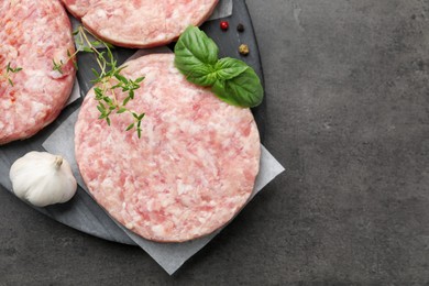 Photo of Fresh raw patties for burger and spices on grey table, top view. Space for text