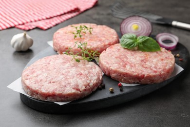 Photo of Fresh raw patties for burger and spices on grey table, closeup