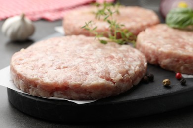 Photo of Fresh raw patties for burger and spices on grey table, closeup