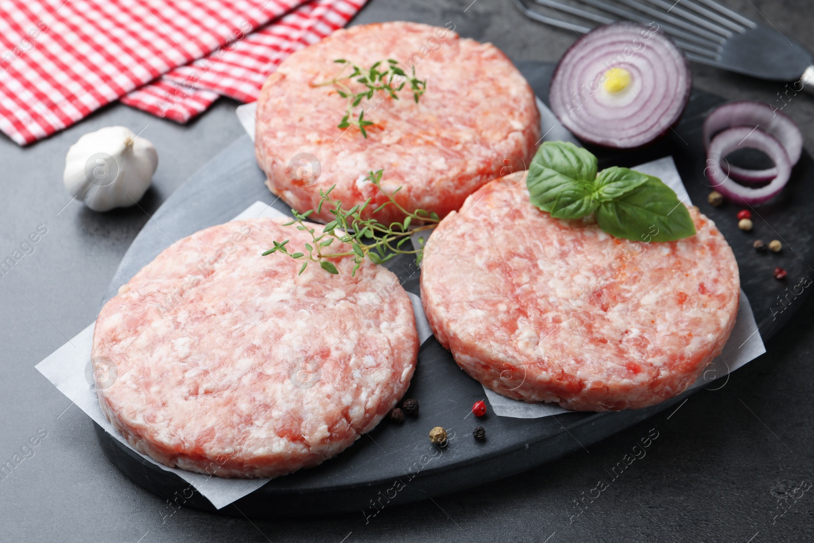 Fresh raw patties for burger and spices on grey table, closeup Photo of Fresh raw patties for burger and spices on grey table, closeup