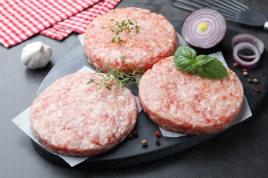 Photo of Fresh raw patties for burger and spices on grey table, closeup