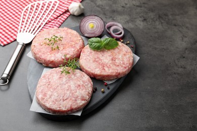 Photo of Fresh raw patties for burger and spices on grey table, closeup. Space for text