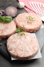 Photo of Fresh raw patties for burger and spices on grey table, closeup
