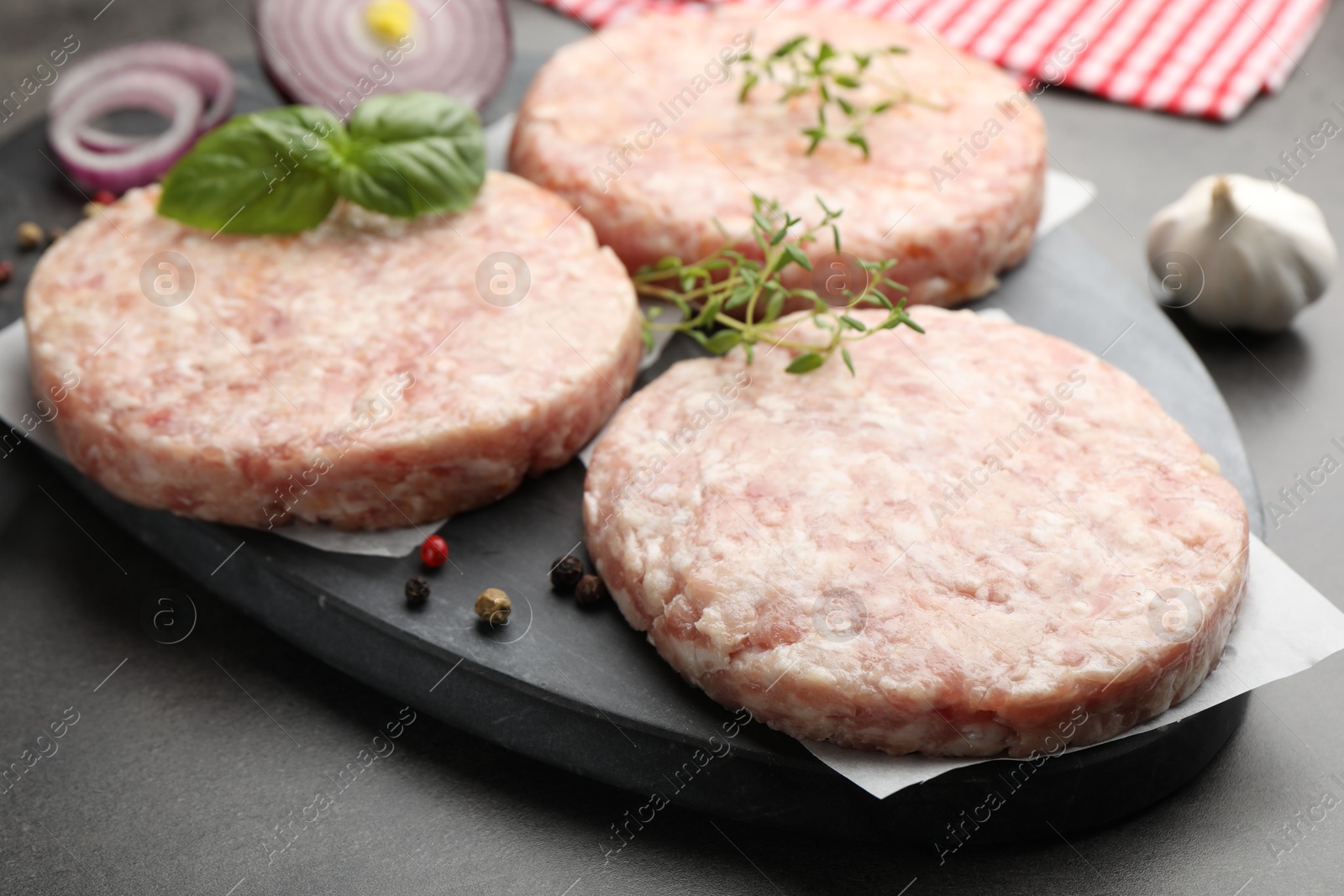 Fresh raw patties for burger and spices on grey table, closeup Photo of Fresh raw patties for burger and spices on grey table, closeup