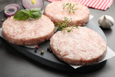 Photo of Fresh raw patties for burger and spices on grey table, closeup