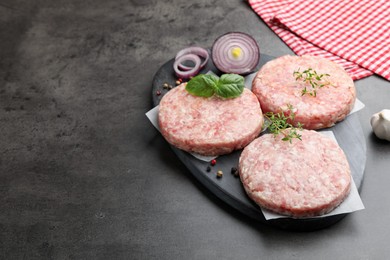 Photo of Fresh raw patties for burger and spices on grey table, closeup. Space for text
