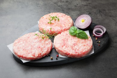 Photo of Fresh raw patties for burger and spices on grey table, closeup