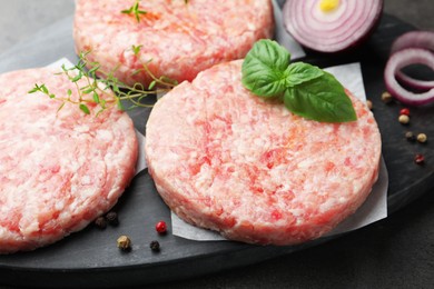Photo of Fresh raw patties for burger and spices on grey table, closeup