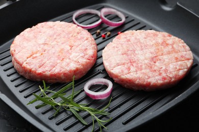 Photo of Fresh raw patties for burger and spices in frying pan on table, closeup