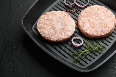 Photo of Fresh raw patties for burger and spices in frying pan on black table, above view