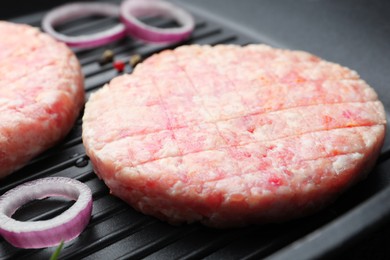 Photo of Fresh raw patties for burger and spices in frying pan, closeup