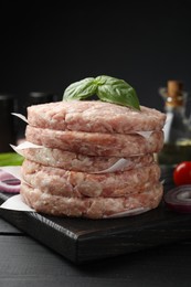 Photo of Fresh raw patties for burger and spices on black wooden table, closeup