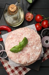 Photo of Fresh raw patties for burger, spices and tomatoes on black wooden table, flat lay