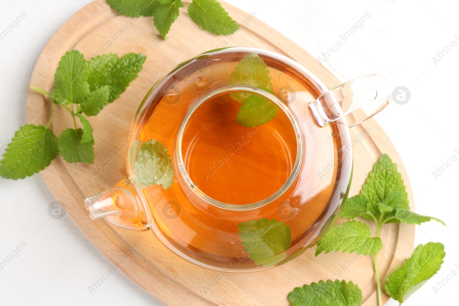 Aromatic lemon balm tea in glass teapot and fresh leaves on white table, top view Photo of Aromatic lemon balm tea in glass teapot and fresh leaves on white table, top view