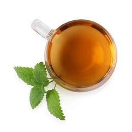 Photo of Aromatic lemon balm tea in glass cup and fresh leaves isolated on white, top view
