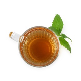 Photo of Aromatic lemon balm tea in glass cup and fresh leaves isolated on white, top view