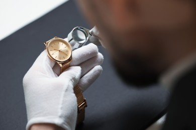 Photo of Appraiser evaluating luxury wristwatch indoors, closeup view