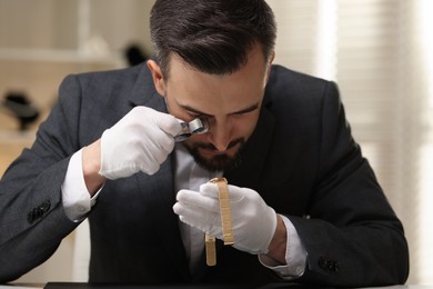Photo of Appraiser with loupe evaluating luxury wristwatch indoors