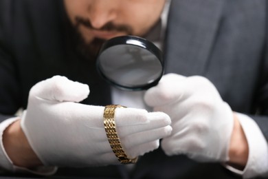 Photo of Appraiser evaluating luxury wristwatch at table indoors, closeup