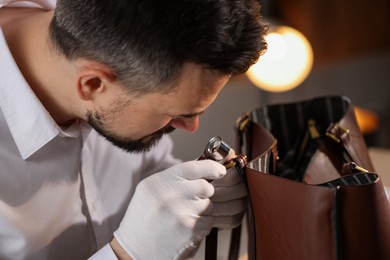 Photo of Appraiser with loupe evaluating leather bag indoors