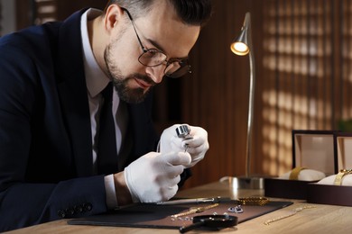 Photo of Appraiser with loupe evaluating ring at table indoors