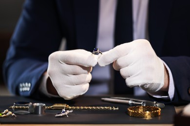 Photo of Appraiser working with luxury ring at table indoors, closeup