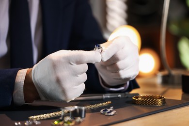 Photo of Appraiser working with luxury ring at table indoors, closeup