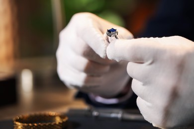 Photo of Appraiser working with luxury ring at table indoors, closeup. Space for text