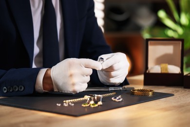 Photo of Appraiser working with luxury ring at table indoors, closeup