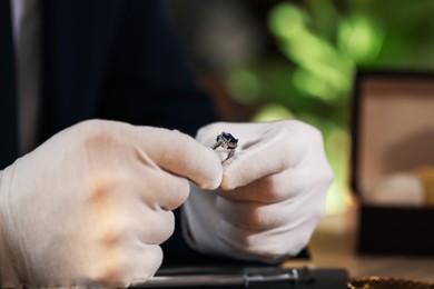 Photo of Appraiser working with luxury ring at table indoors, closeup