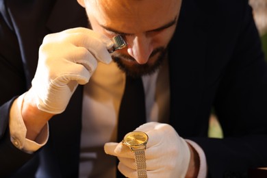 Photo of Appraiser with loupe evaluating luxury wristwatch indoors
