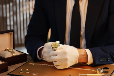 Photo of Appraiser working with luxury wristwatch at table indoors, closeup