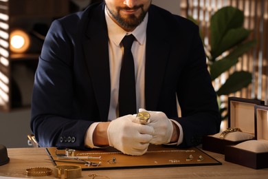 Photo of Appraiser working with luxury wristwatch at table indoors, closeup