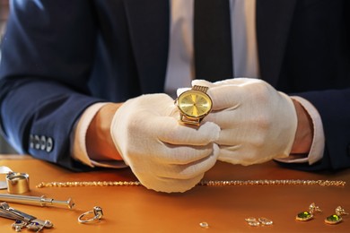 Photo of Appraiser working with luxury wristwatch at table, closeup