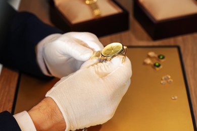 Photo of Appraiser working with luxury wristwatch at table, closeup