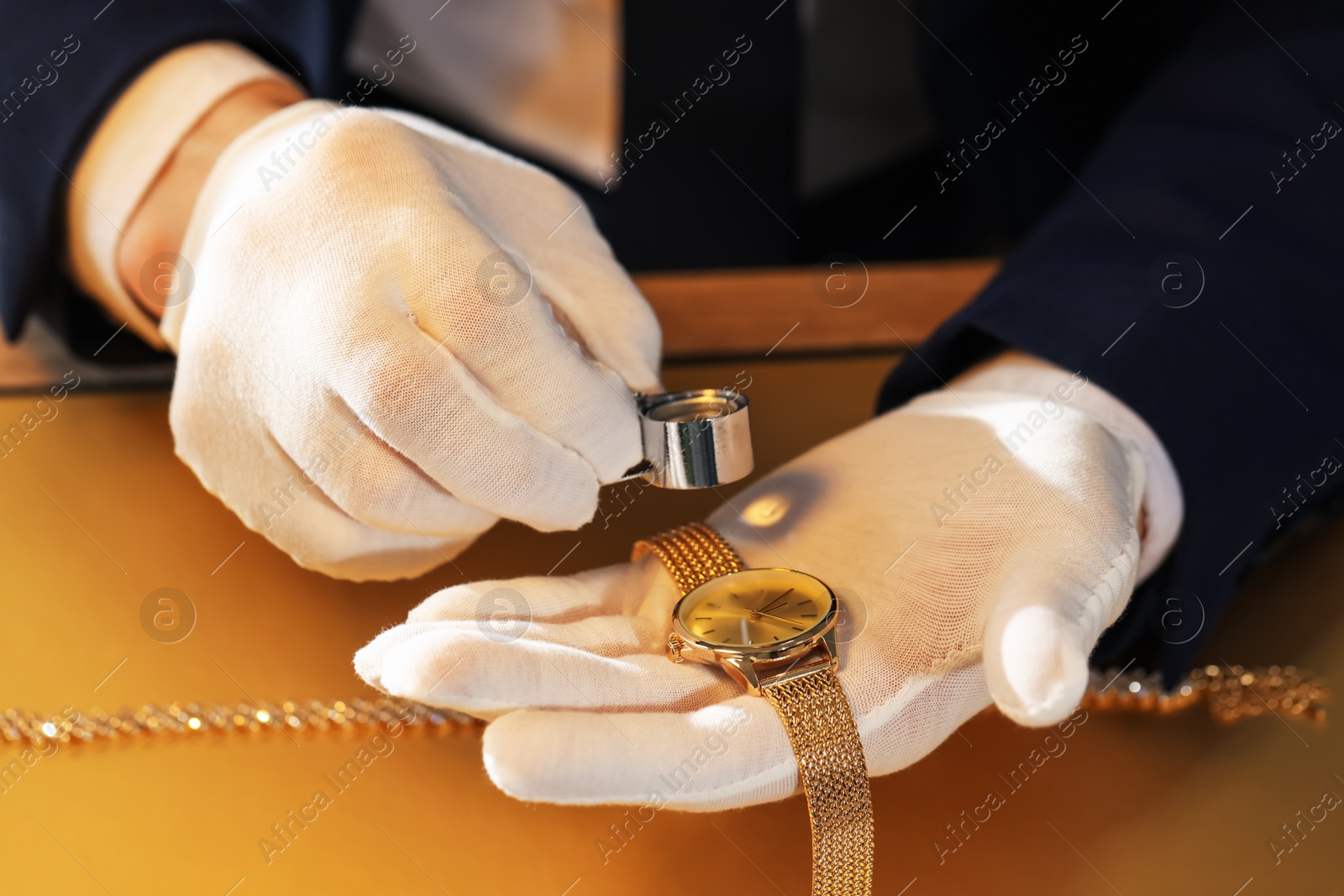 Appraiser with loupe evaluating luxury wristwatch at table, closeup Photo of Appraiser with loupe evaluating luxury wristwatch at table, closeup