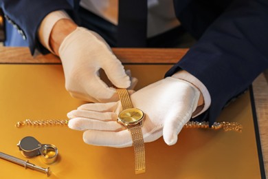 Photo of Appraiser working with luxury wristwatch at table, above view