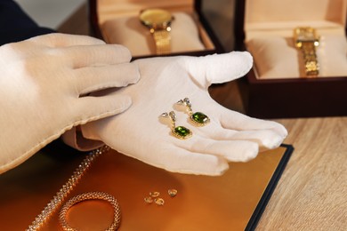 Photo of Appraiser working with luxury earrings at table, closeup