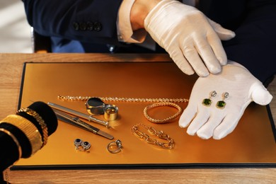 Photo of Appraiser working with luxury earrings at table, closeup