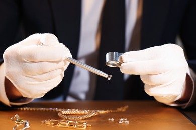 Photo of Appraiser with loupe evaluating luxury gemstone at table, closeup